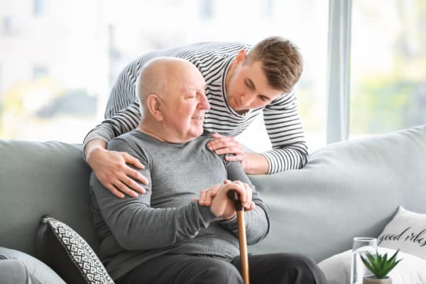 Younger man hugging older man on couch, memory loss, memory screen. AD research